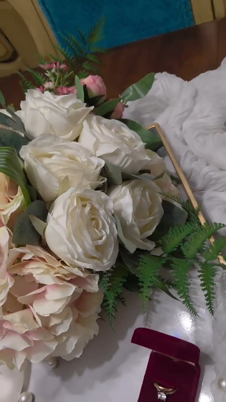 Cream garden roses and blush hydrangea bridal bouquet in premium silk, resting on ivory fabric